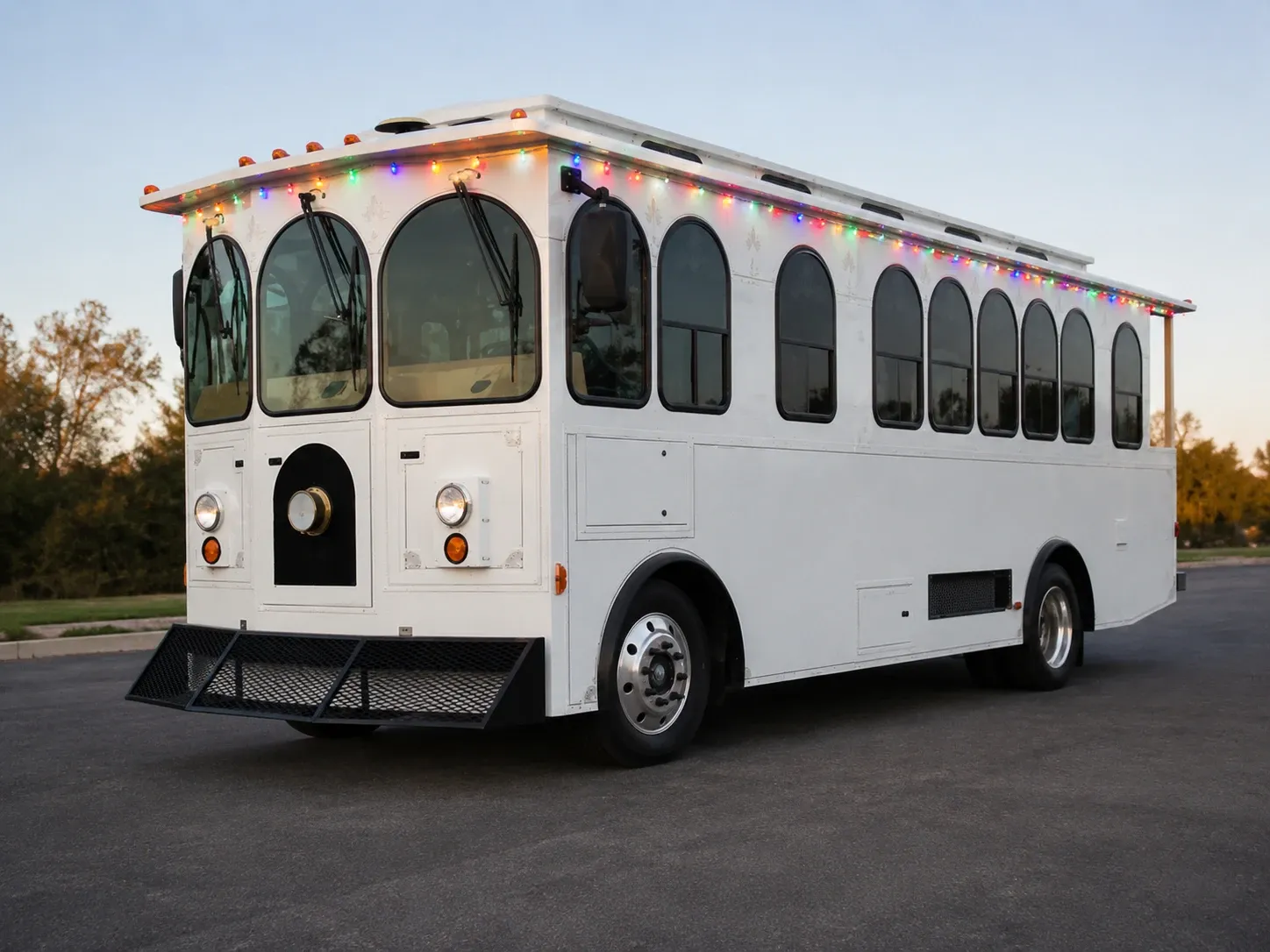 The Christmas Trolley at dusk, with strings of colored lights along its roofline and arched windows.