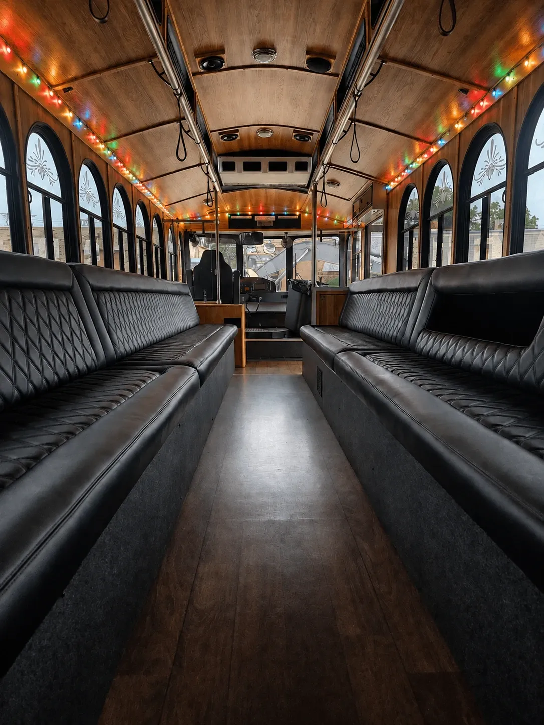 Inside the Christmas Trolley: black quilted perimeter benches beneath a wood ceiling lined with colored lights.