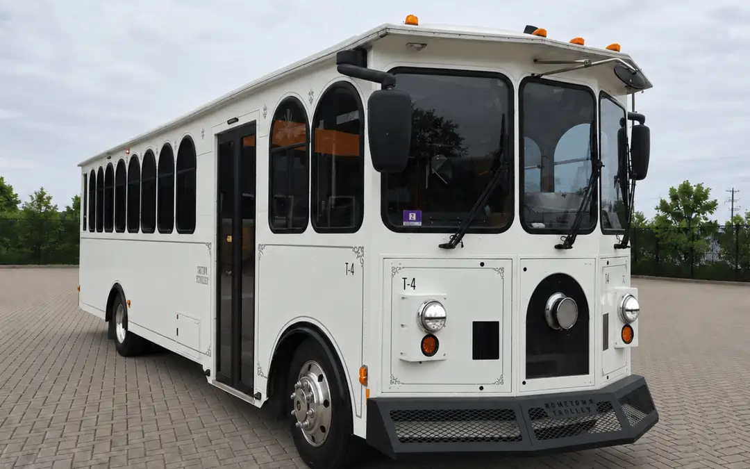 A white trolley parked on a paver drive, front three-quarter view.