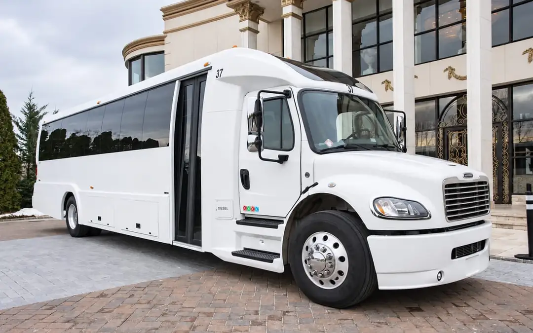 A white party bus waiting at a venue entrance with its door open.