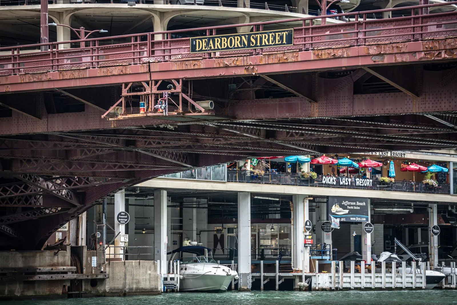 The Dearborn Street bridge over the Chicago Riverwalk, with café umbrellas along the water.