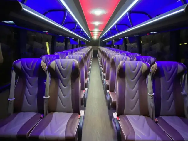 Reclining coach bus seats under blue accent lighting.